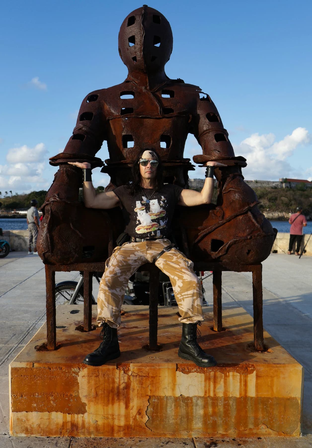 Yoss sentado en la escultura del Malecón de La Habana